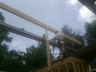 Carpenter setting a ridge beam over a new addition frame — Ice Dam Removal by Roofing Brothers in Shevlin