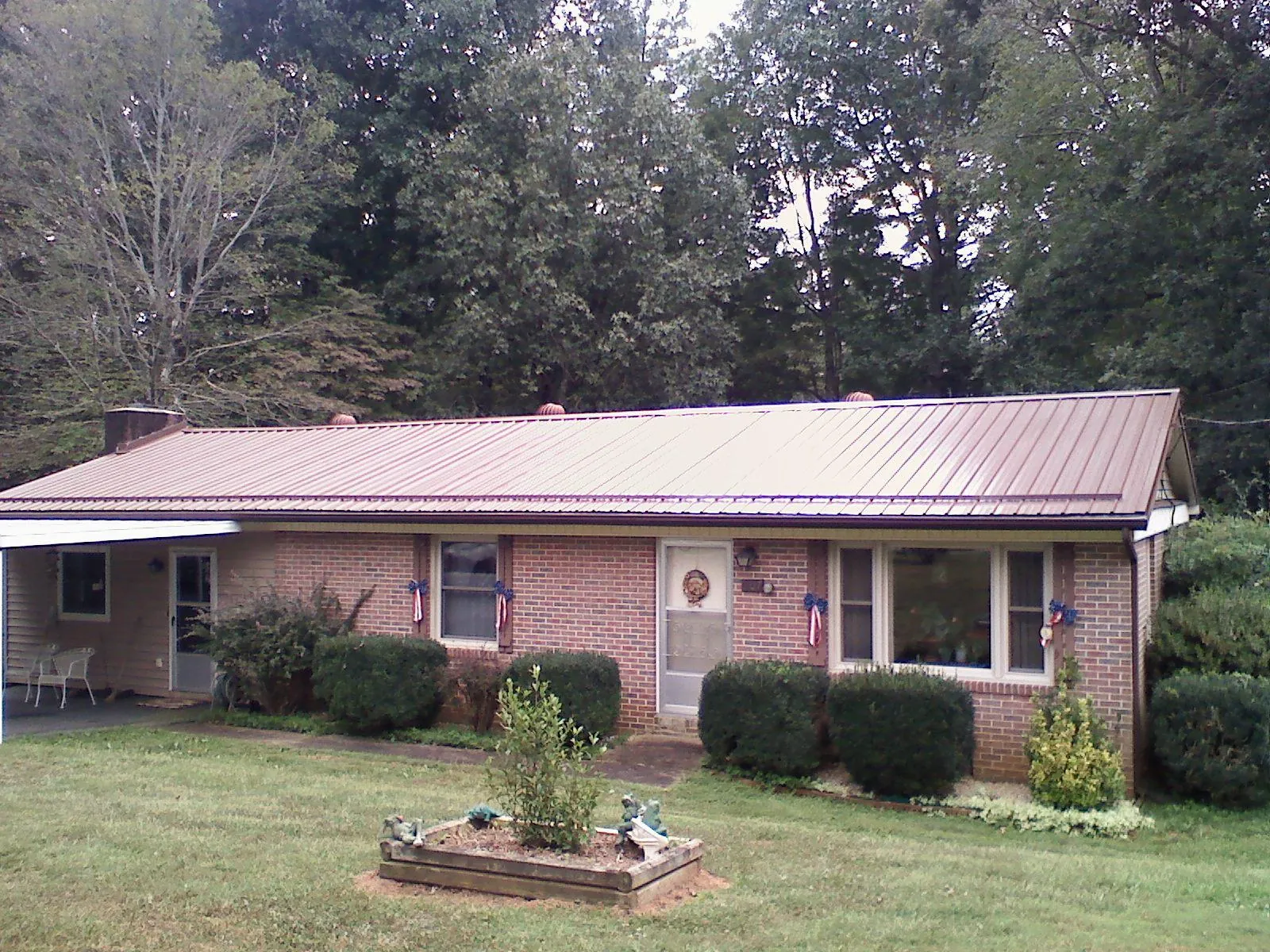 Bronze metal roof on a brick ranch home with a carport in Shevlin