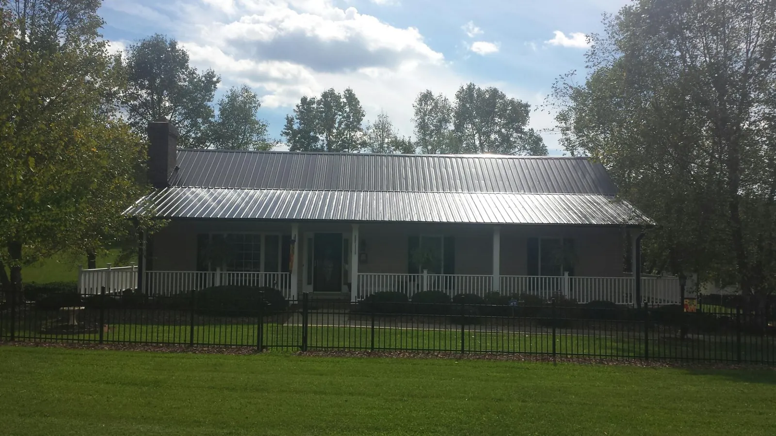 Gray metal roof on a brick ranch with a full width front porch — Gutter Guard Installation work by our crew in Shevlin